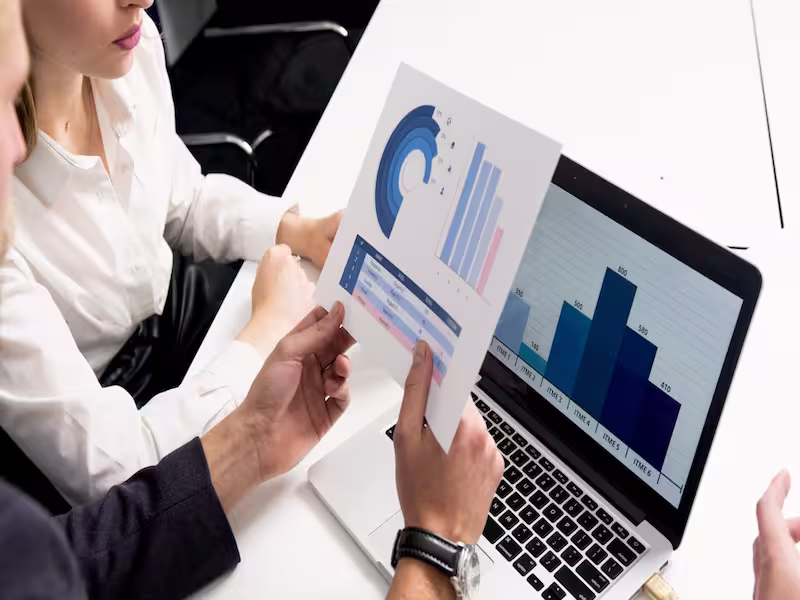 Two people looking at stock movements and bar charts.