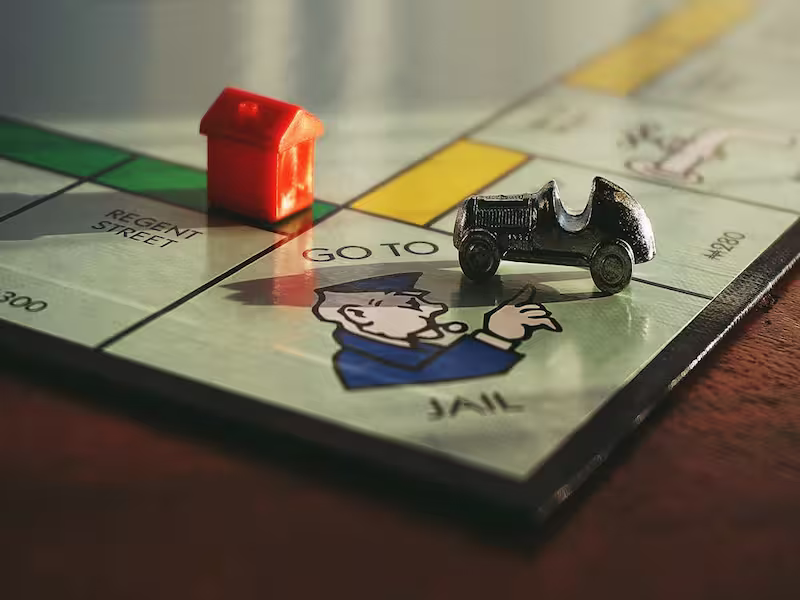 The board game monopoly with a car sitting on the go to jail square